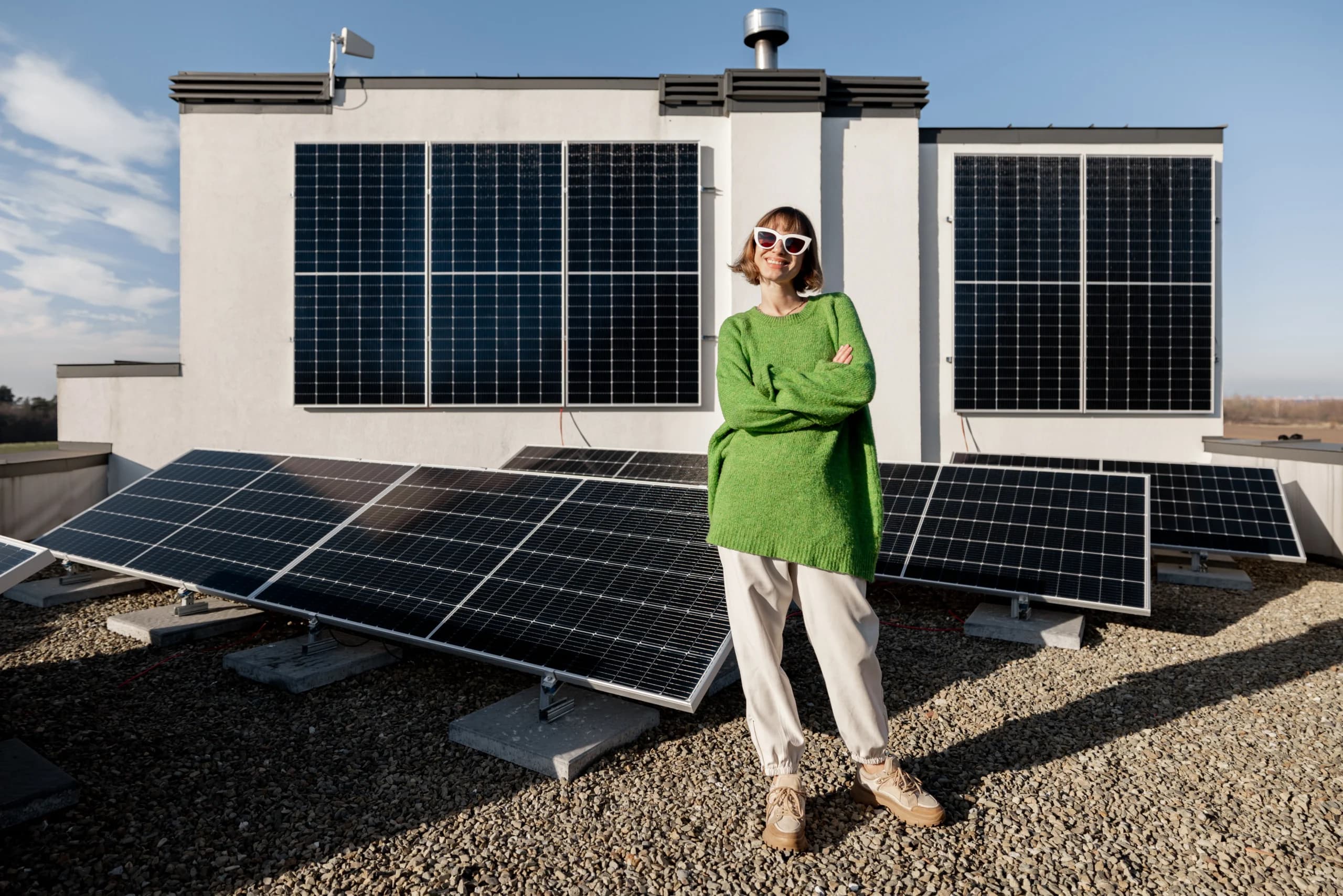 A woman is happily standing in front of her newly installed solar panels.