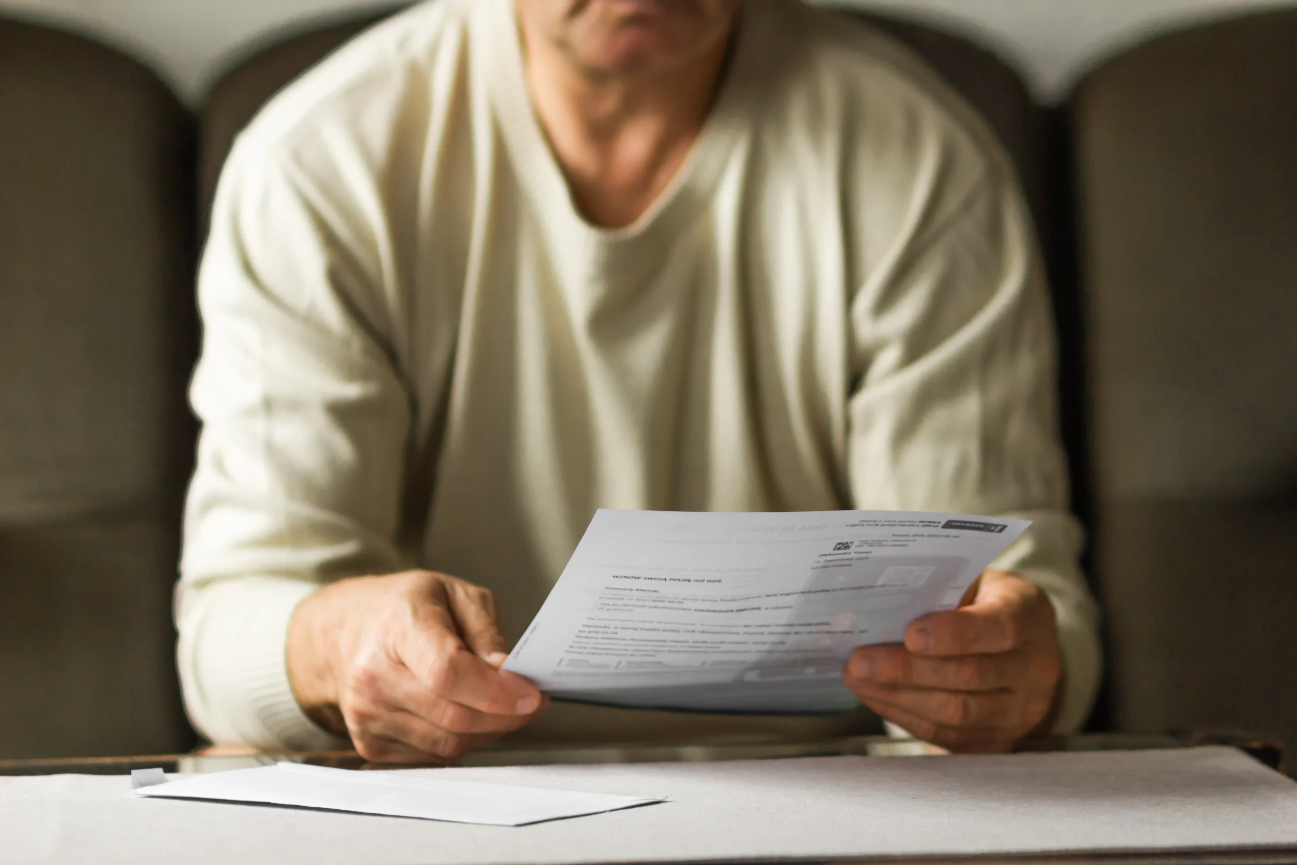 Man is holding is paper bill, reading it.