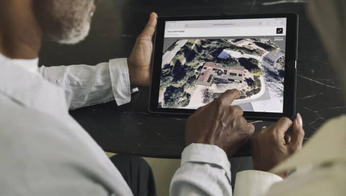 Two individuals examining an aerial view of a property on a tablet screen