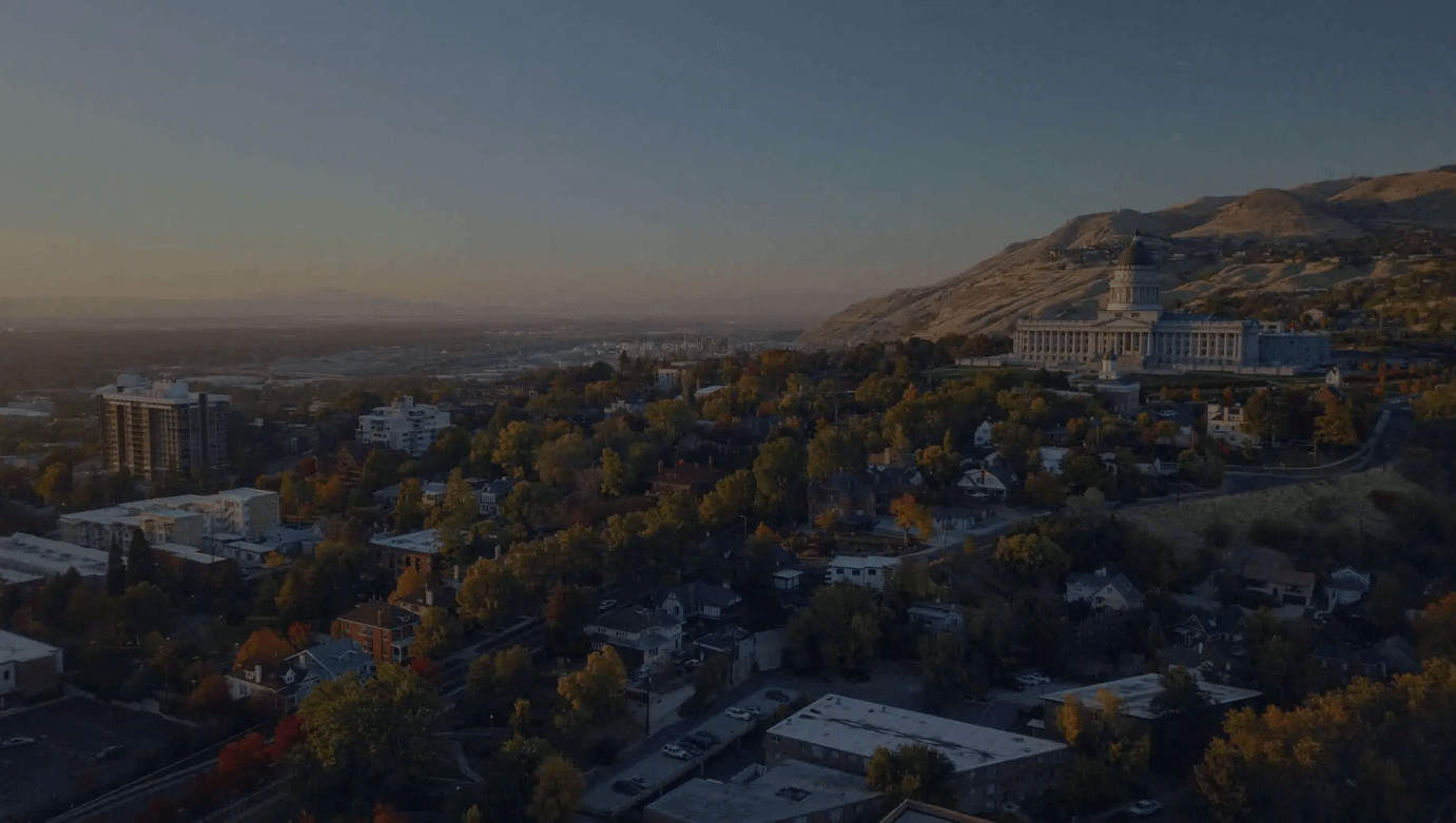 Dusk settles over a tranquil cityscape with a prominent building on the hillside overlooking the urban area below.